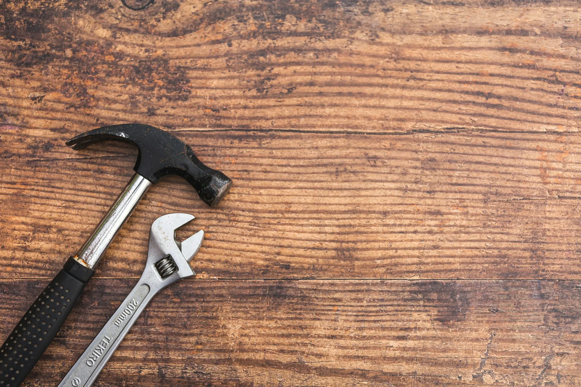 Claw hammer and adjustable wrench on a wood table